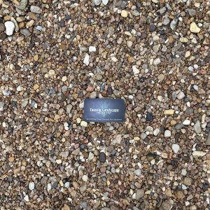 A black business card for Tranquil Landscapes lies on a surface covered with small, multicolored pebbles.